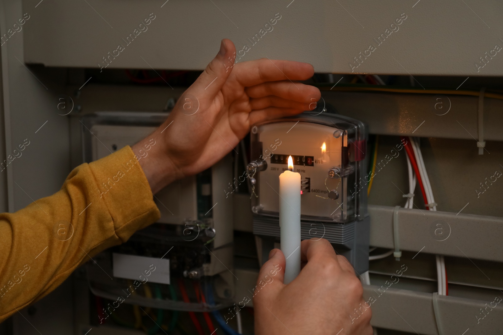 Photo of Man with candle checking electricity meter indoors, closeup