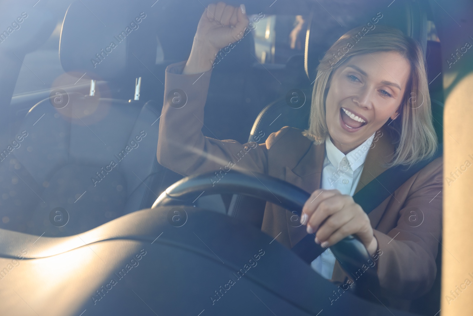 Photo of Woman singing in car, view through windshield