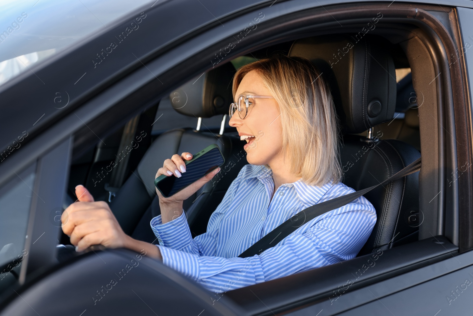 Photo of Woman with smartphone singing in car, view from outside