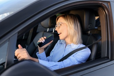 Woman with smartphone singing in car, view from outside