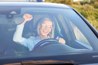 Photo of Woman singing in car, view through windshield