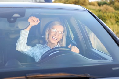 Woman singing in car, view through windshield