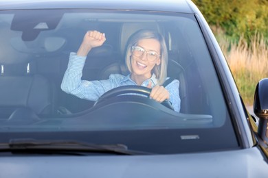 Woman singing in car, view through windshield