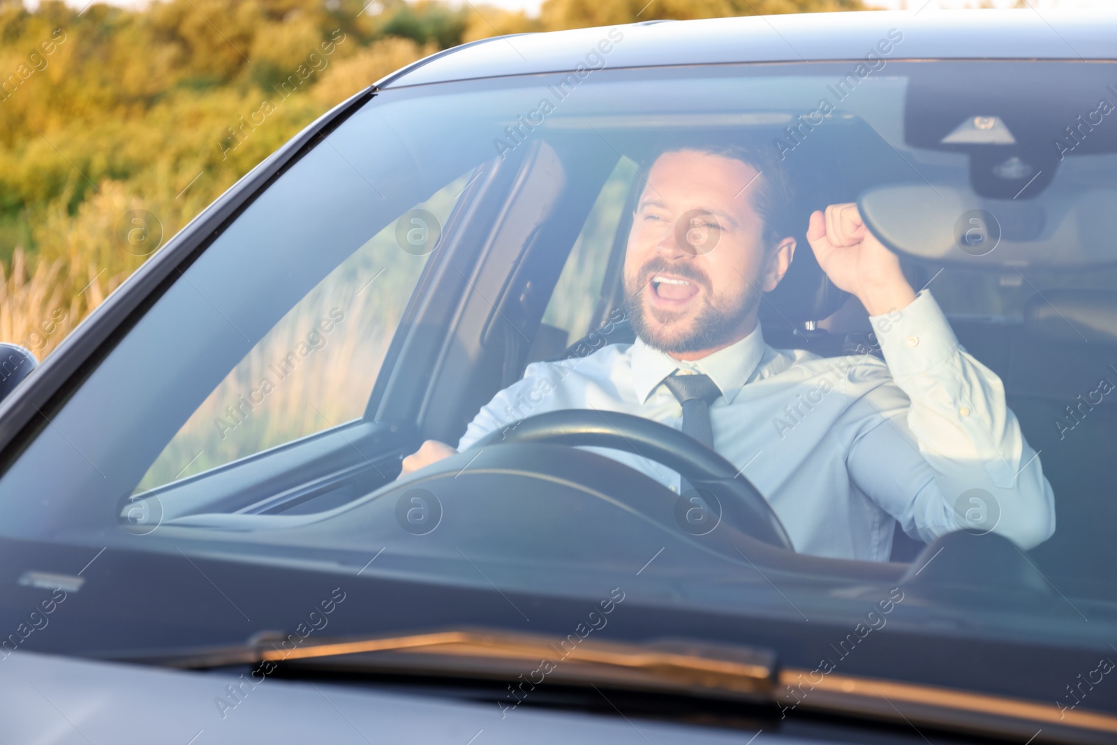 Photo of Man singing in car, view through windshield