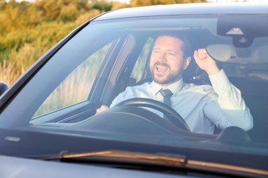 Man singing in car, view through windshield