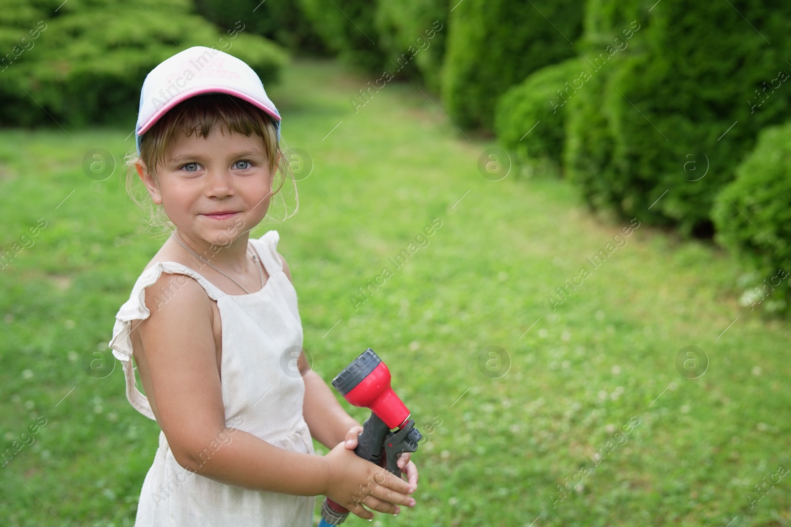 Photo of Little girl with hose in backyard, space for text