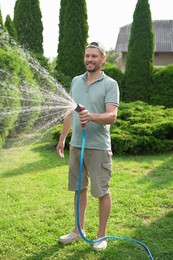 Man watering lawn with hose in backyard