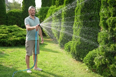 Man watering lawn with hose in backyard