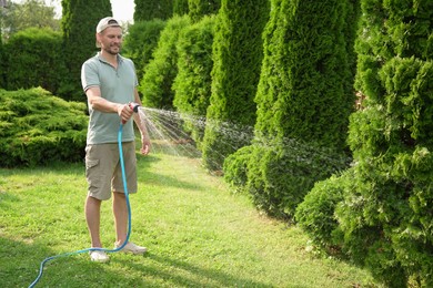 Man watering lawn with hose in backyard