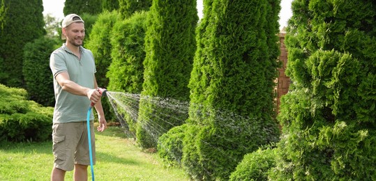 Man watering lawn with hose in backyard