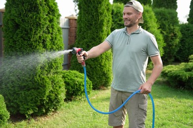 Man watering lawn with hose in backyard