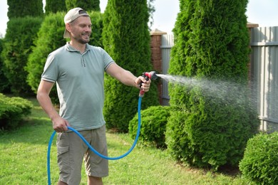 Man watering lawn with hose in backyard