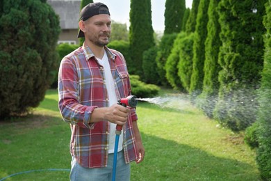 Man watering lawn with hose in backyard