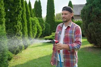 Man watering lawn with hose in backyard