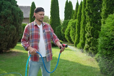 Photo of Man watering lawn with hose in backyard