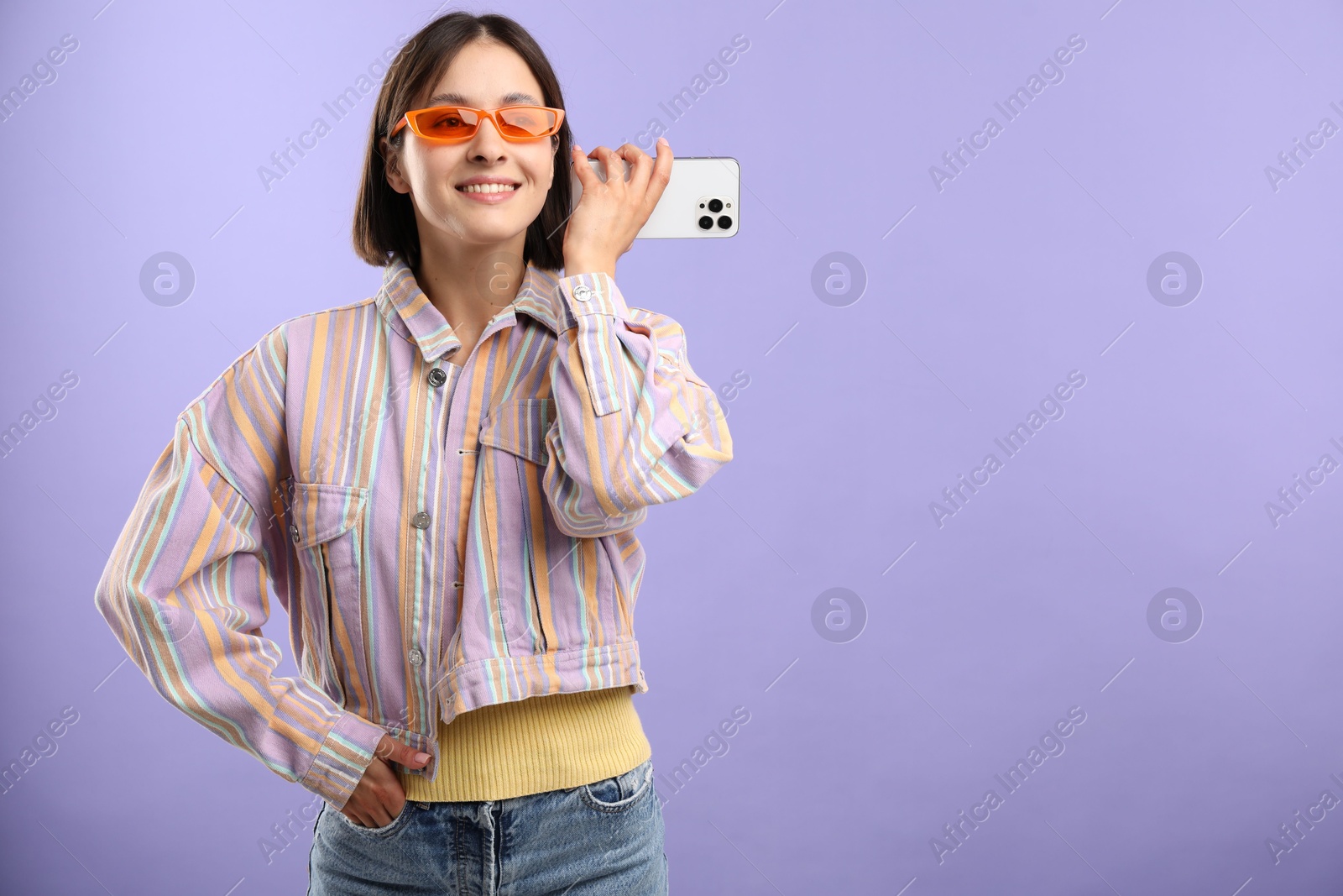 Photo of Beautiful woman in sunglasses with smartphone listening to voice message on violet background, space for text