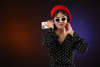 Stylish woman listening to voice message via smartphone on color background, space for text