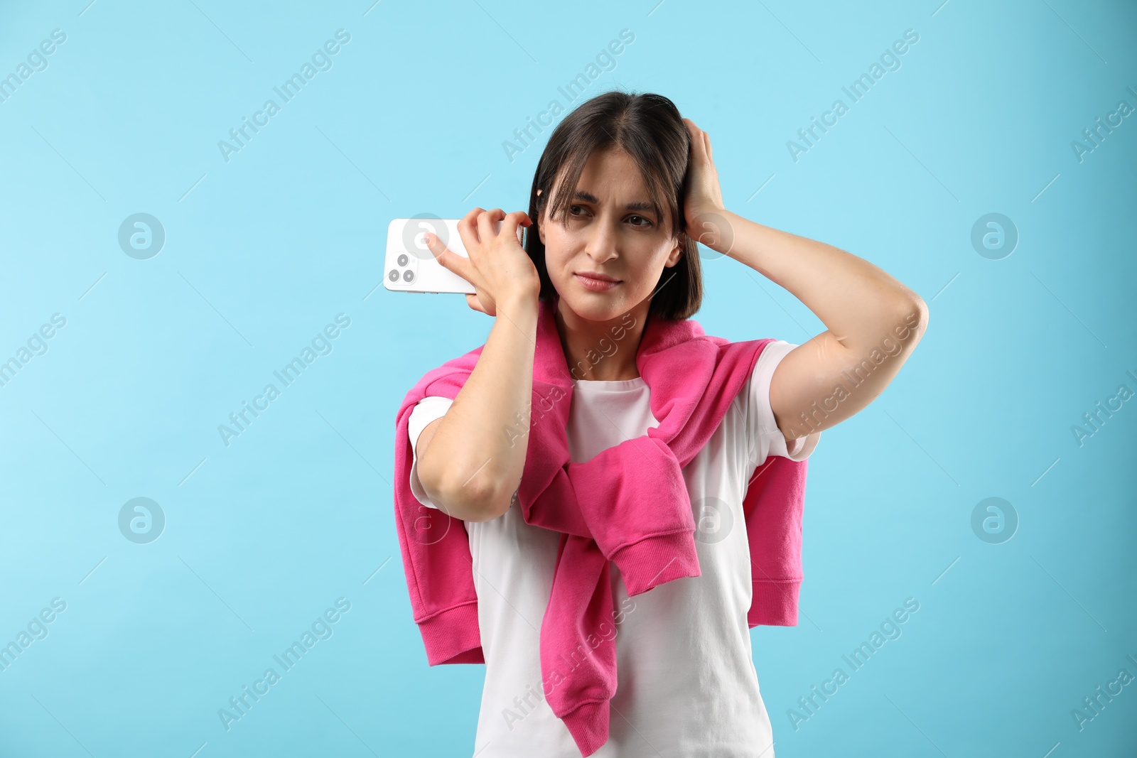 Photo of Beautiful woman with smartphone listening to voice message on light blue background