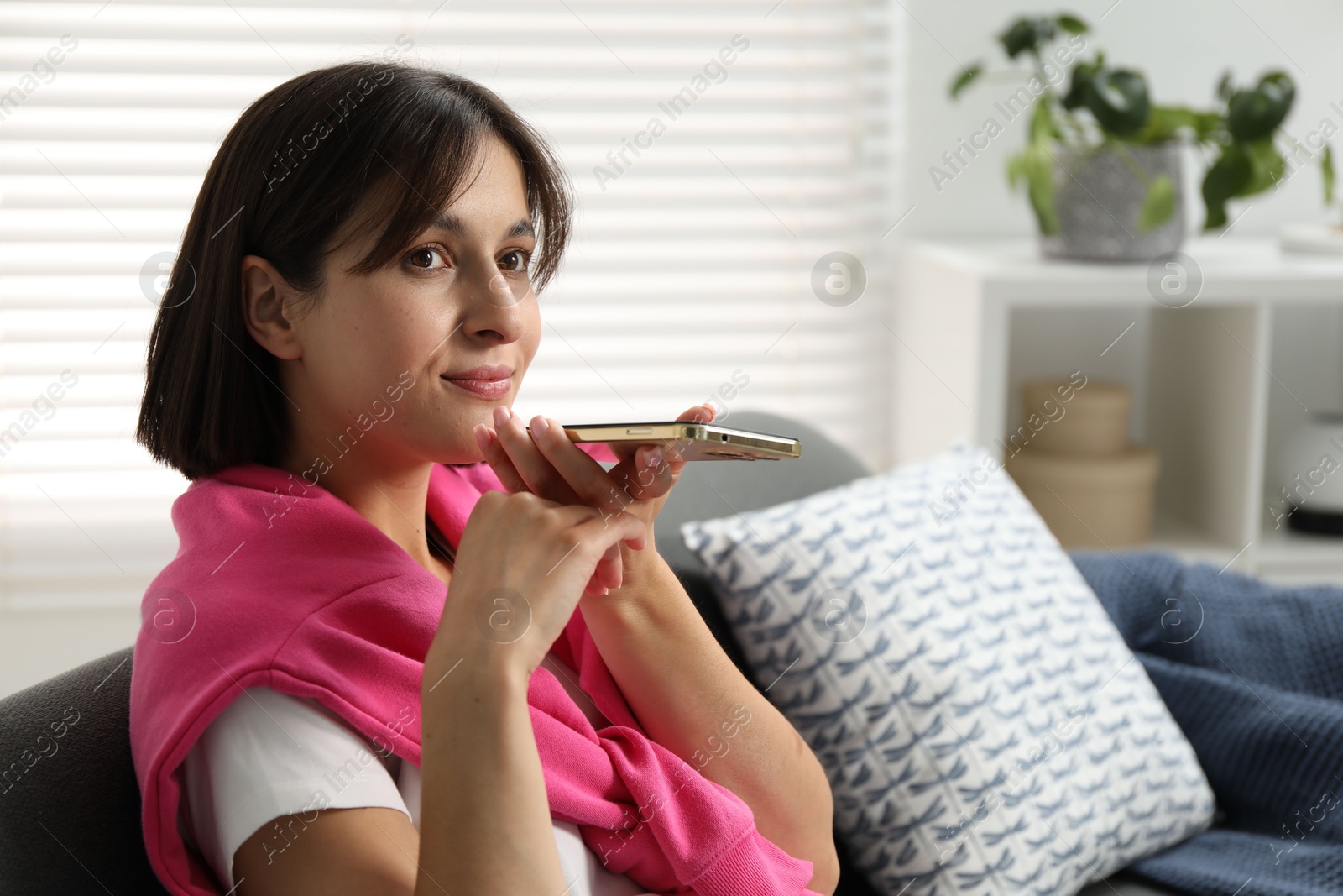 Photo of Beautiful woman recording voice message via smartphone at home