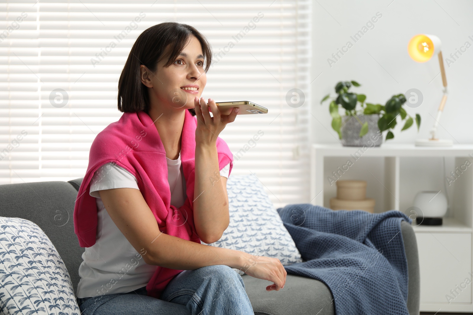 Photo of Beautiful woman recording voice message via smartphone at home