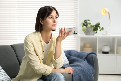 Photo of Beautiful woman recording voice message via smartphone at home