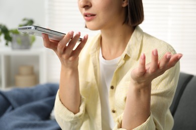 Photo of Woman recording voice message via smartphone at home, closeup