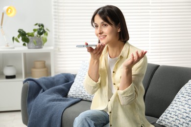 Photo of Beautiful woman recording voice message via smartphone at home