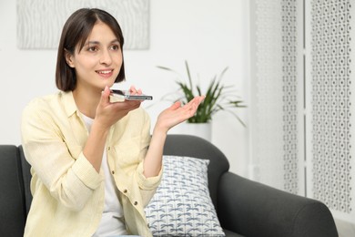 Photo of Beautiful woman recording voice message via smartphone at home