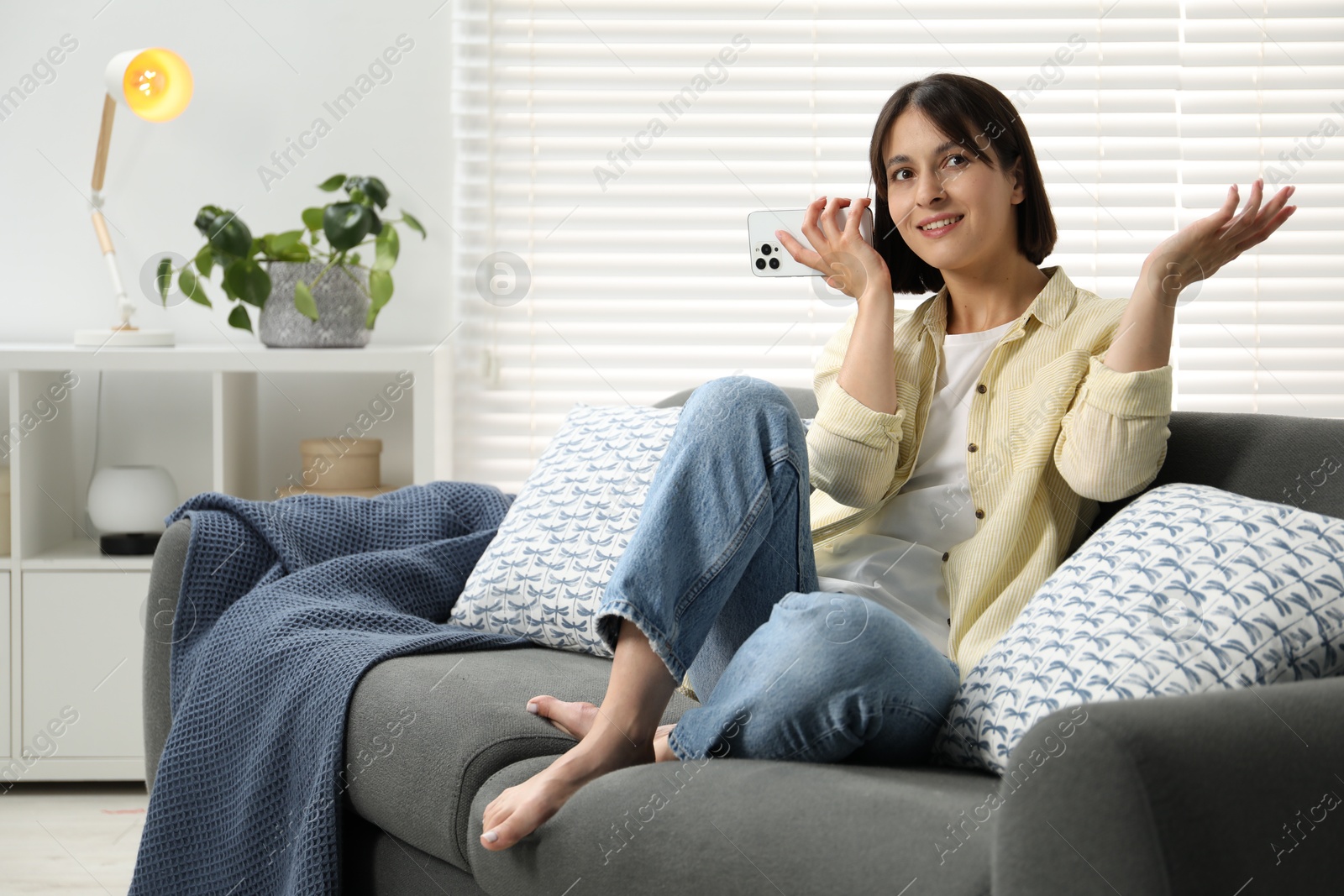 Photo of Beautiful woman with smartphone listening to voice message at home