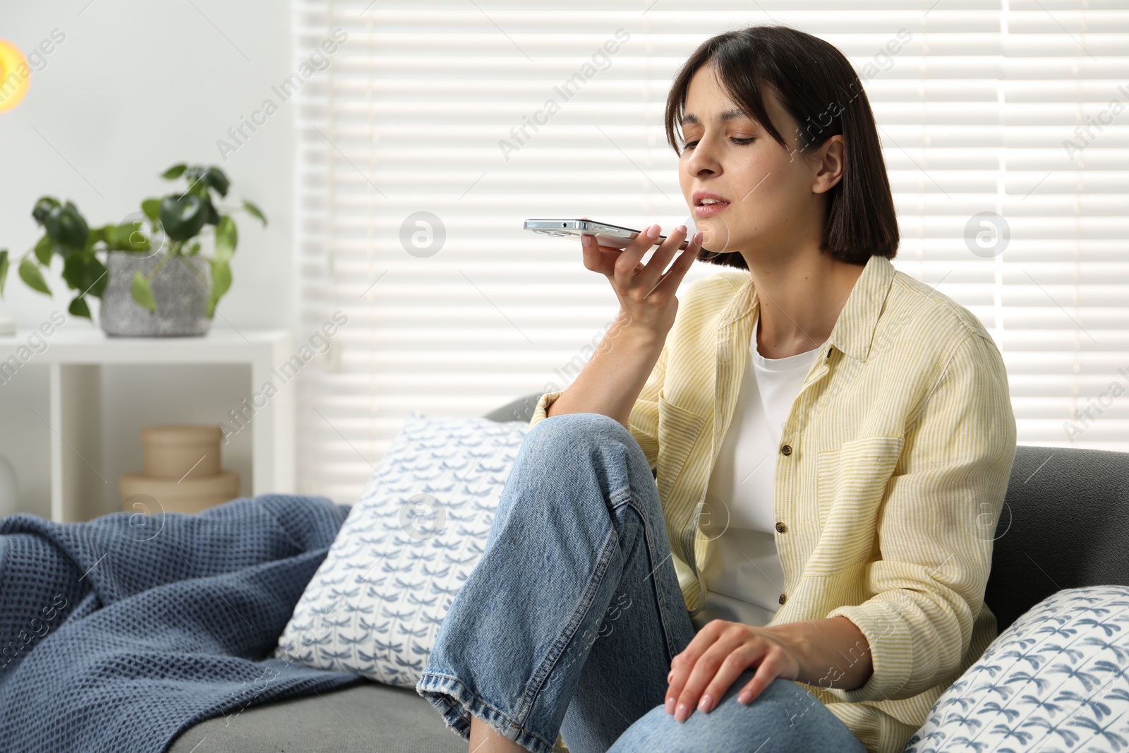 Photo of Beautiful woman recording voice message via smartphone at home