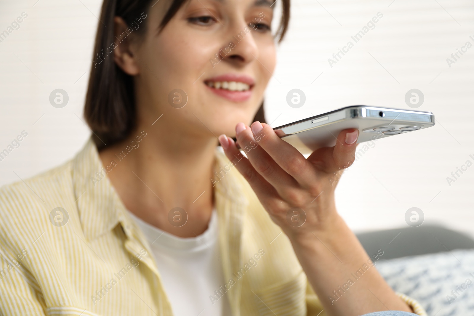 Photo of Beautiful woman recording voice message via smartphone at home, selective focus