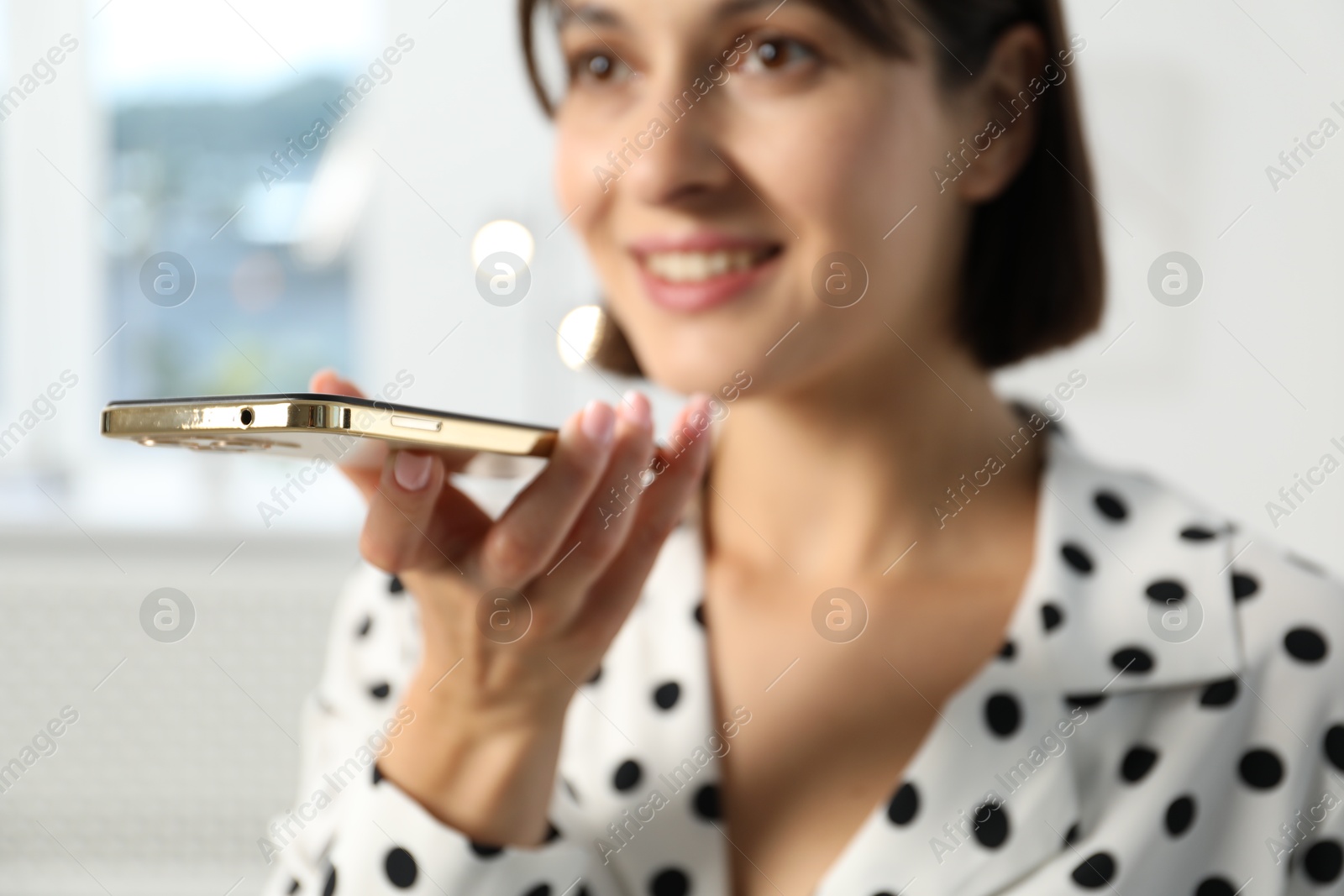 Photo of Beautiful woman recording voice message via smartphone in office, selective focus