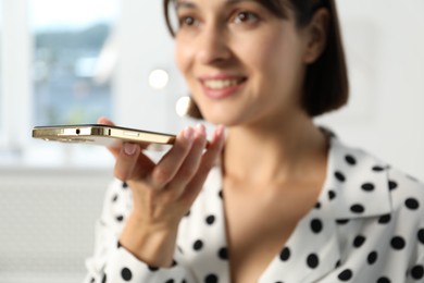 Photo of Beautiful woman recording voice message via smartphone in office, selective focus