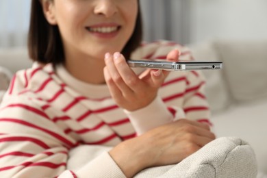 Photo of Woman recording voice message via smartphone at home, closeup