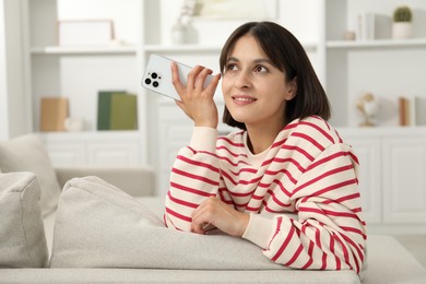 Photo of Beautiful woman with smartphone listening to voice message at home