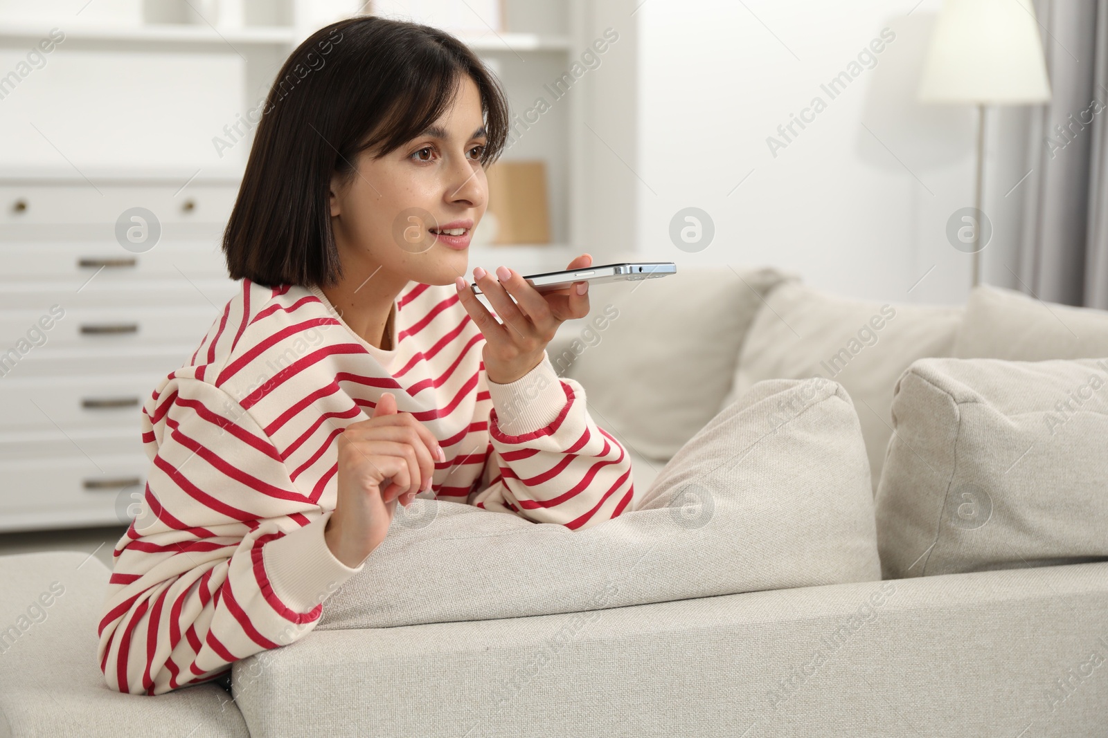 Photo of Beautiful woman recording voice message via smartphone at home