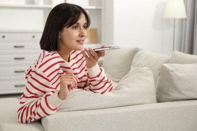 Photo of Beautiful woman recording voice message via smartphone at home