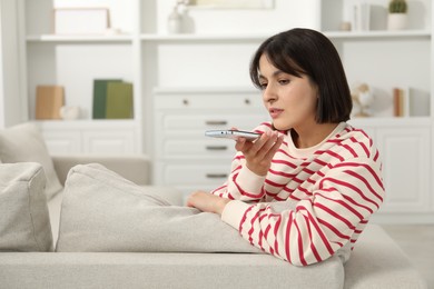 Photo of Beautiful woman recording voice message via smartphone at home