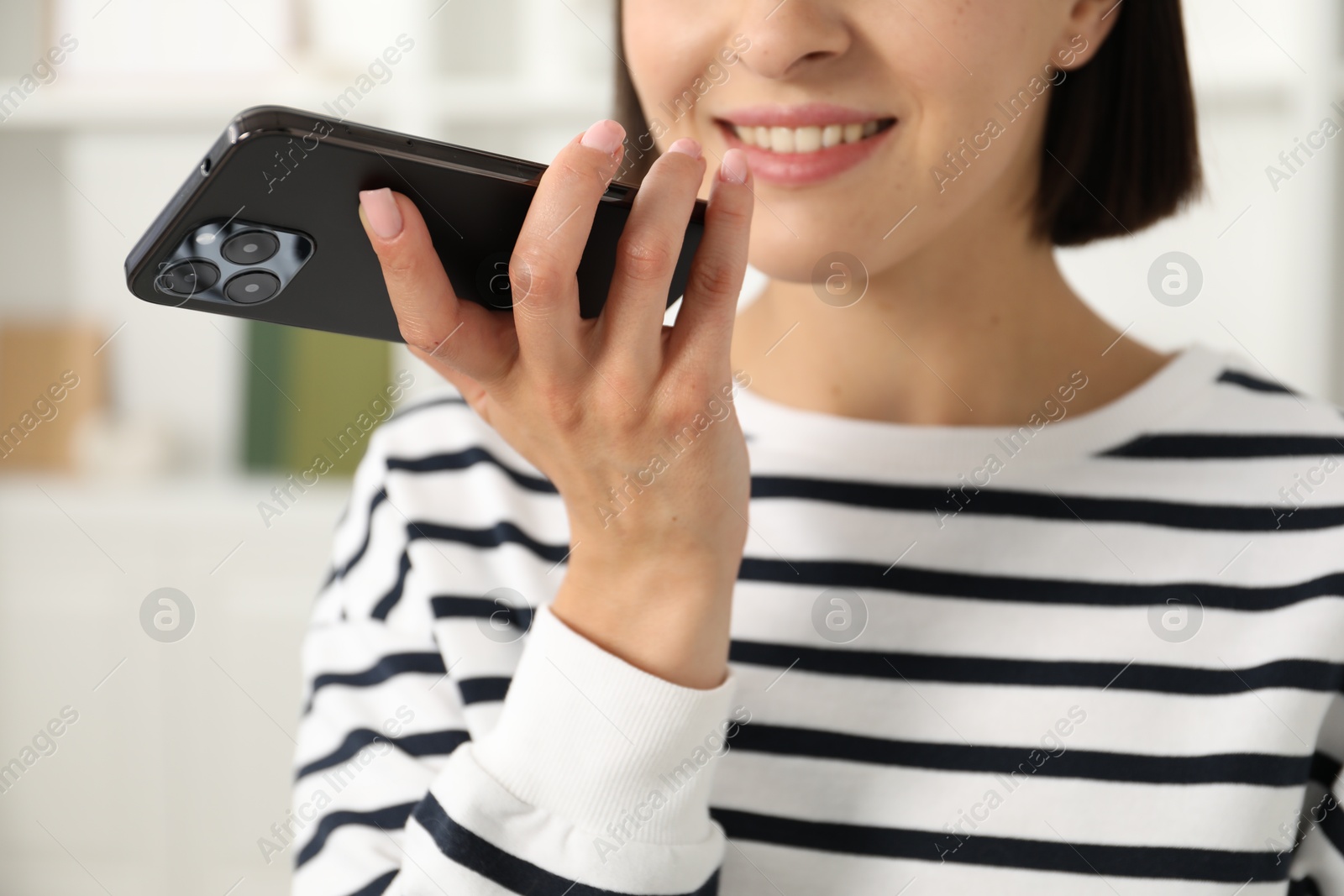 Photo of Woman recording voice message via smartphone at home, closeup