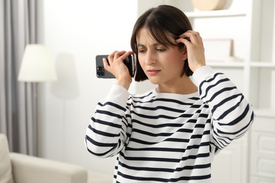 Photo of Beautiful woman with smartphone listening to voice message at home