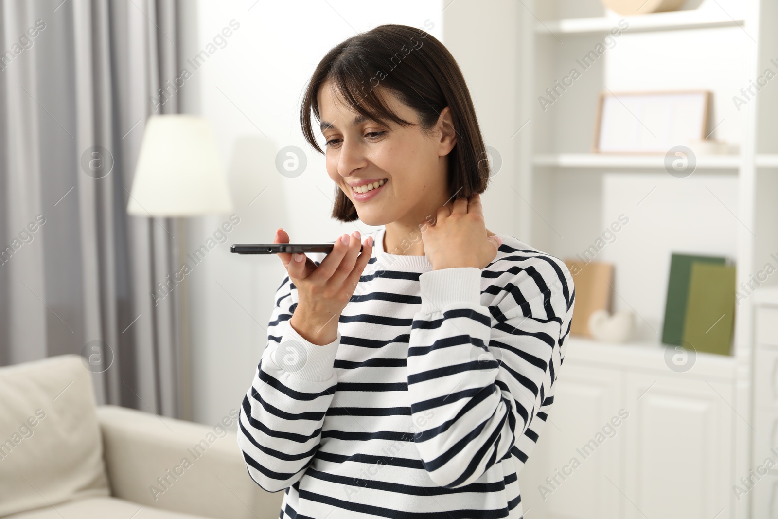 Photo of Beautiful woman recording voice message via smartphone at home