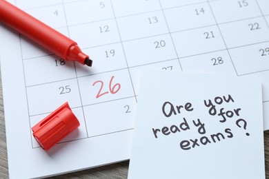 Photo of Note with question Are You Ready For Exams, calendar and marker on wooden desk, closeup