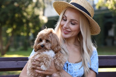 Beautiful young woman with cute dog on bench in park