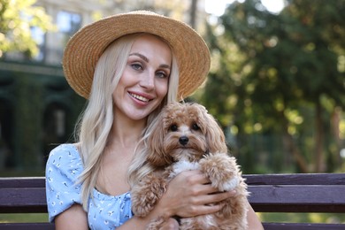 Beautiful young woman with cute dog on bench in park