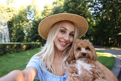 Photo of Beautiful young woman taking selfie with cute dog in park