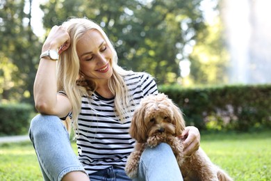 Photo of Beautiful young woman with cute dog on green grass in park