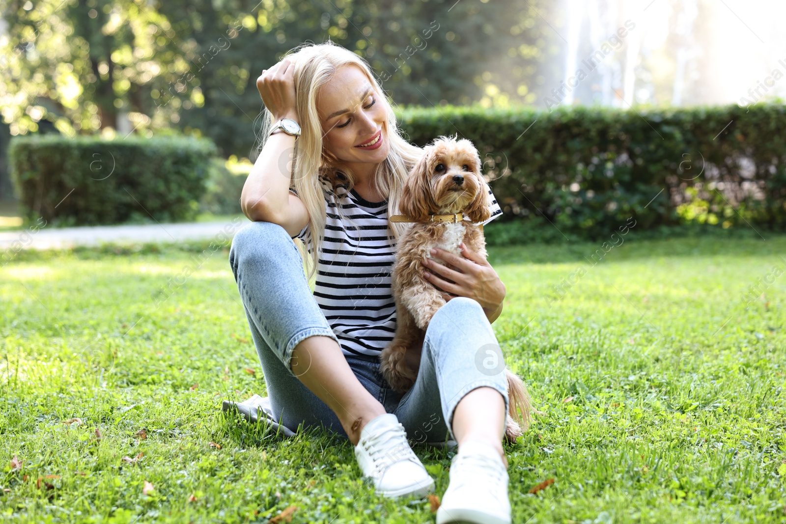 Photo of Beautiful young woman with cute dog on green grass in park