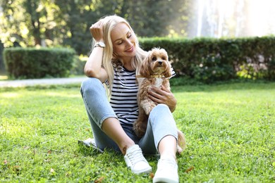 Beautiful young woman with cute dog on green grass in park