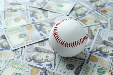 Photo of Baseball ball on many dollars bills, closeup