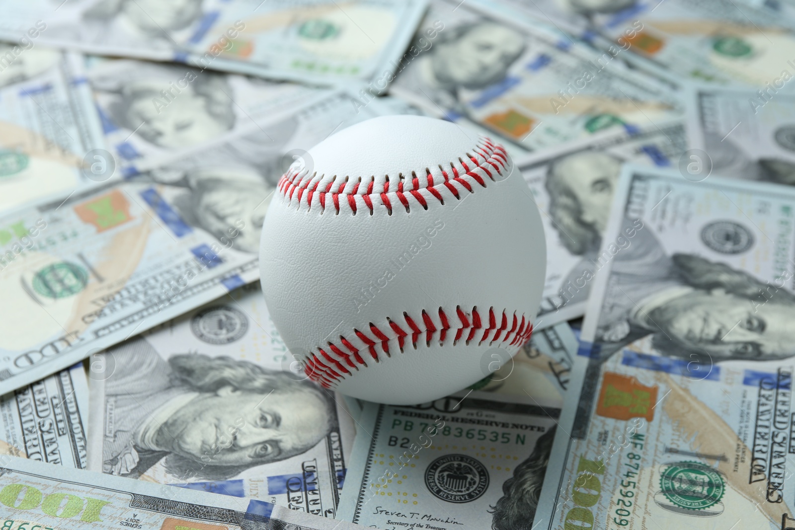 Photo of Baseball ball on many dollars bills, closeup